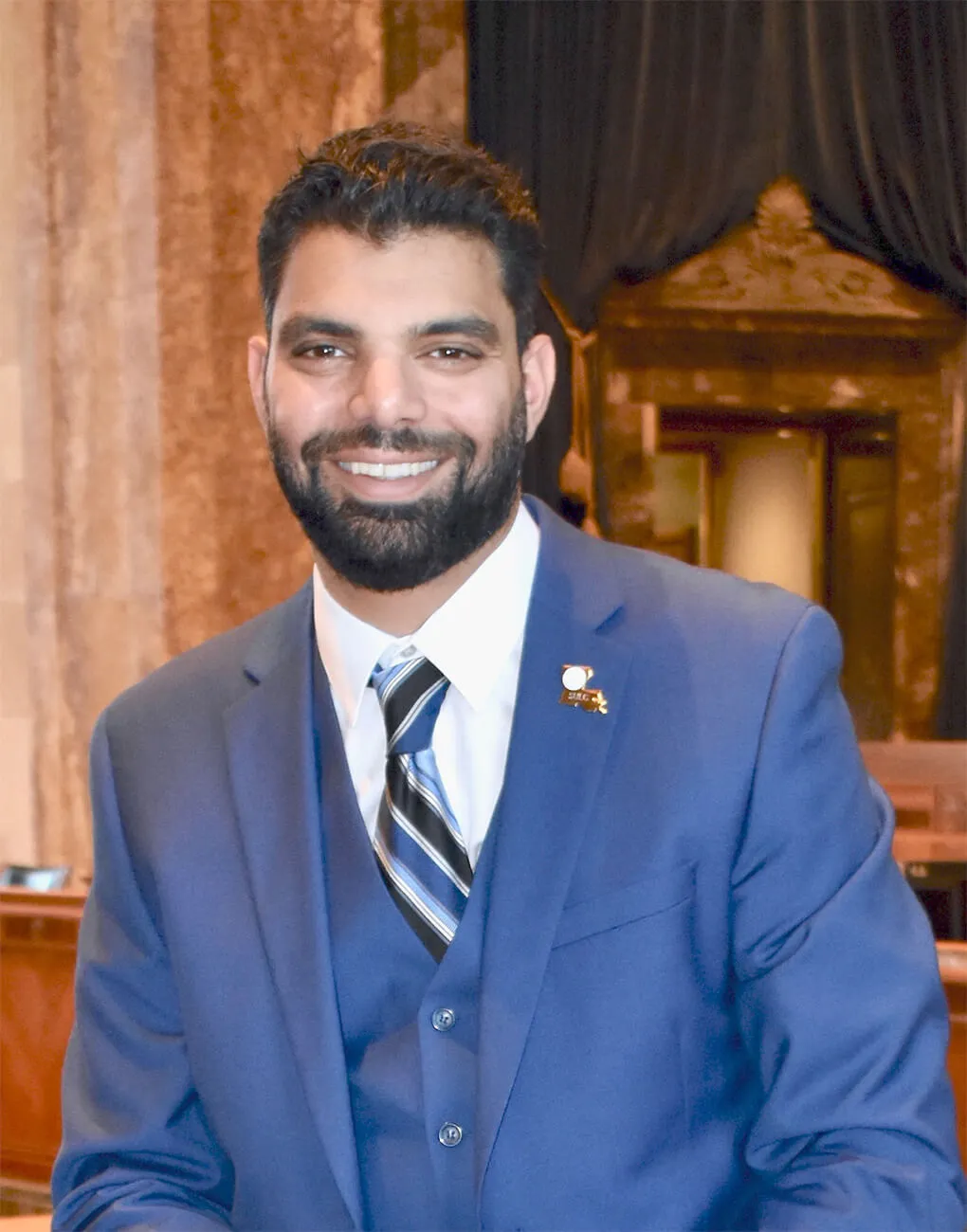 Portrait of attorney Jamil M. Naji in a blue suit, smiling.